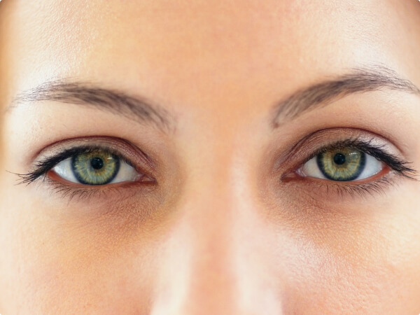 Close-up shot of a woman's face focused on her green eyes. 
