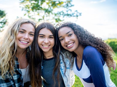 Three teenage girls smiling at the camera. 