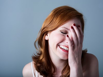 A woman laughing with her hand covering half of her face. 