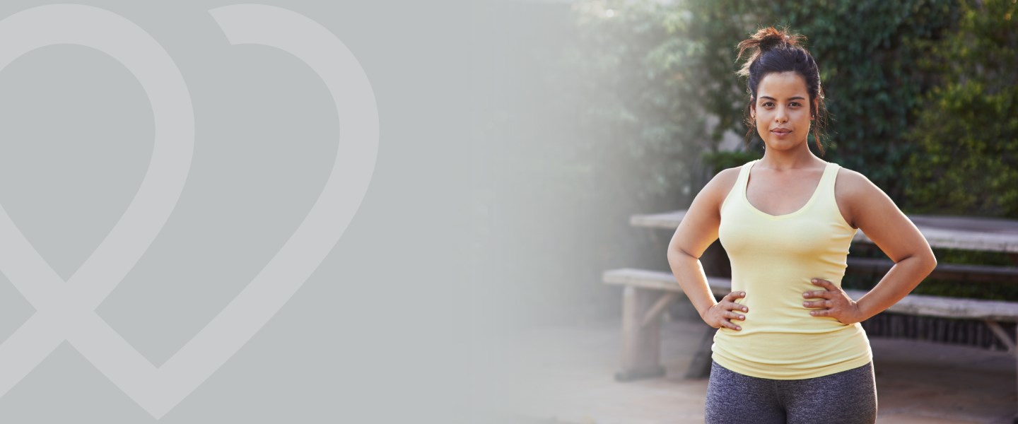 A woman in exercise clothes with her hands on her hips staring at the camera. 