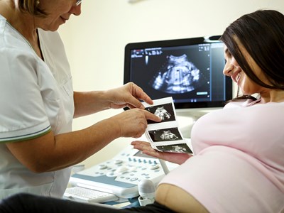 A doctor showing a pregnant woman her ultrasound photos. 