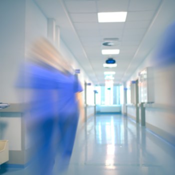 A nurse moving fast inside a hospital hallway. 