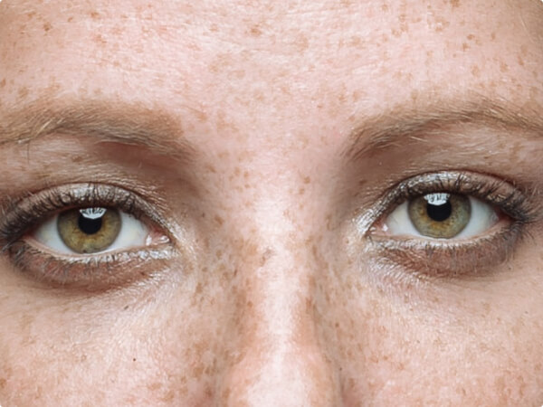 Close-up shot of a woman's face focused on her green eyes. 