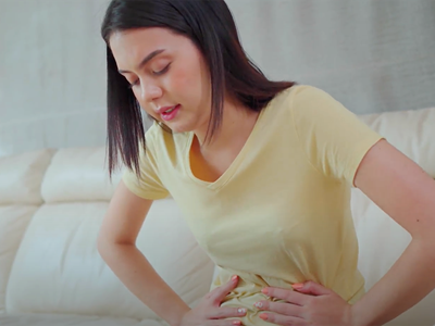 A woman hunched over holding her stomach as if she is in pain. 
