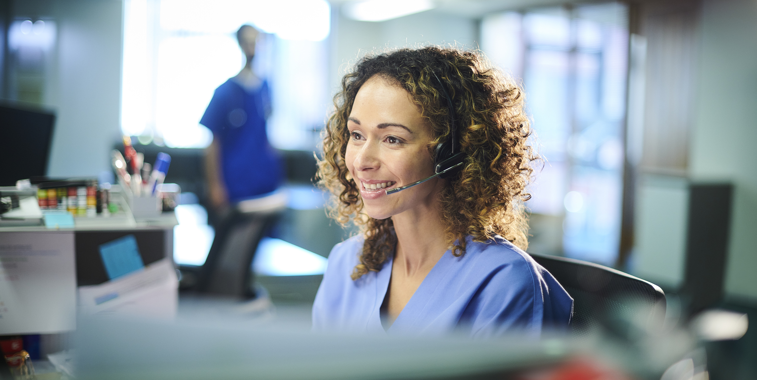 Woman at a desk with a headset on.