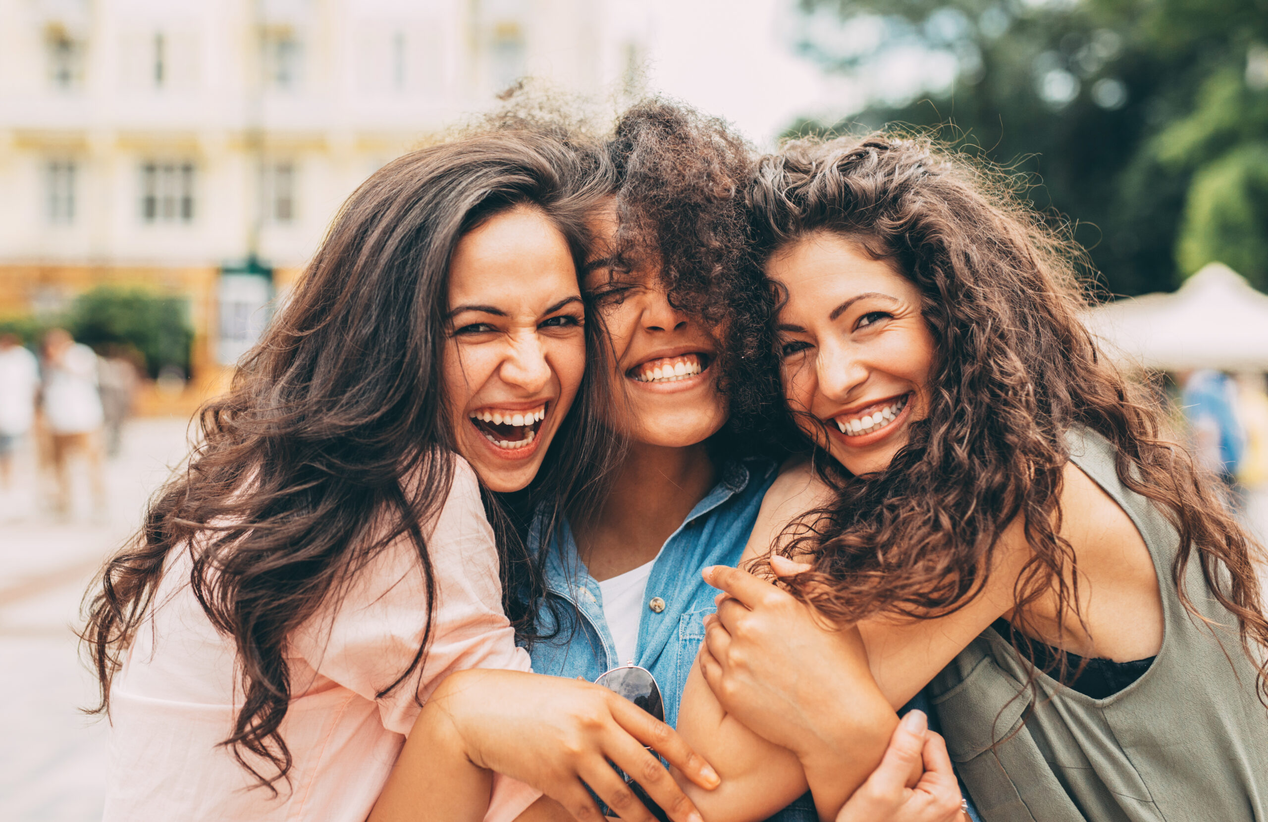 three woman hugging and smiling