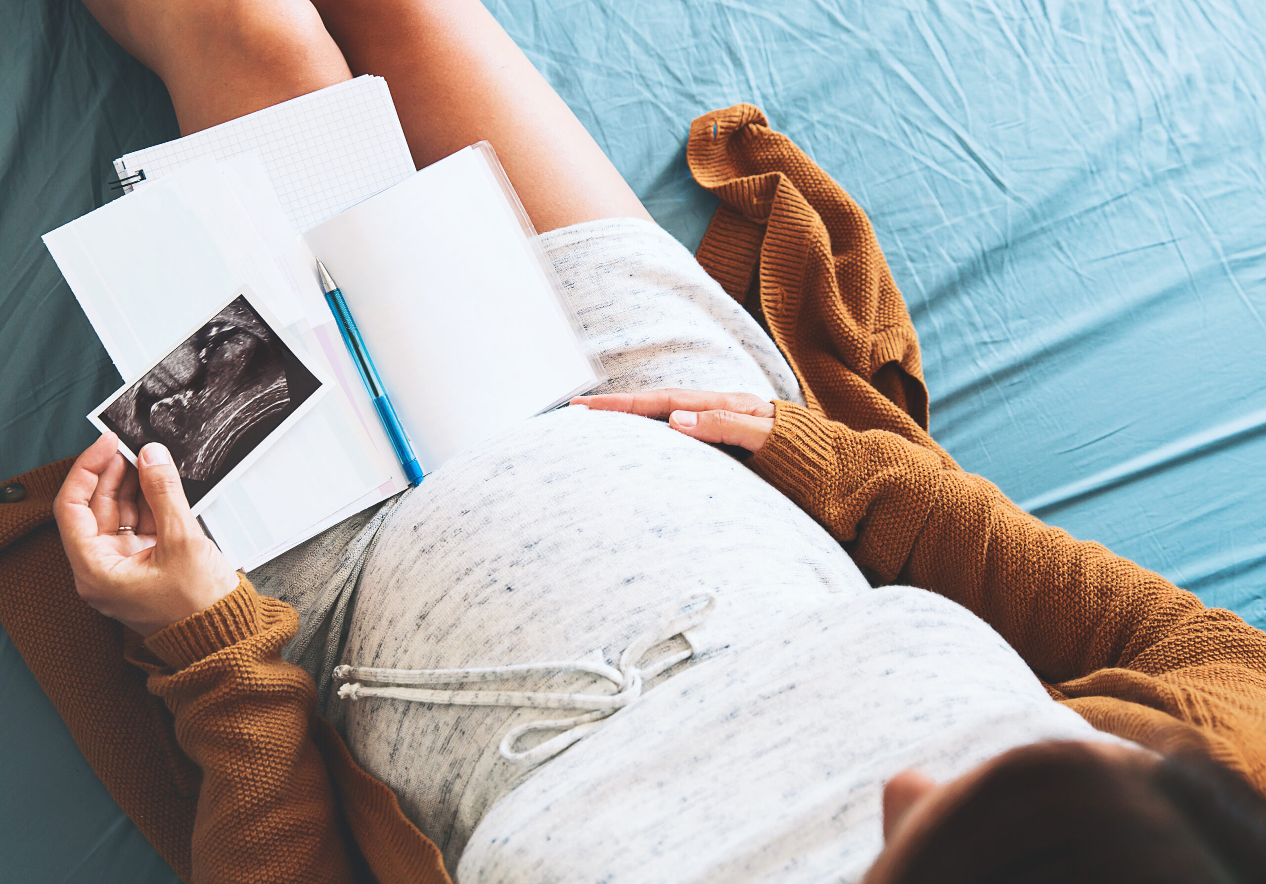 overhead shot of a pregnant woman looking down at ultrasound