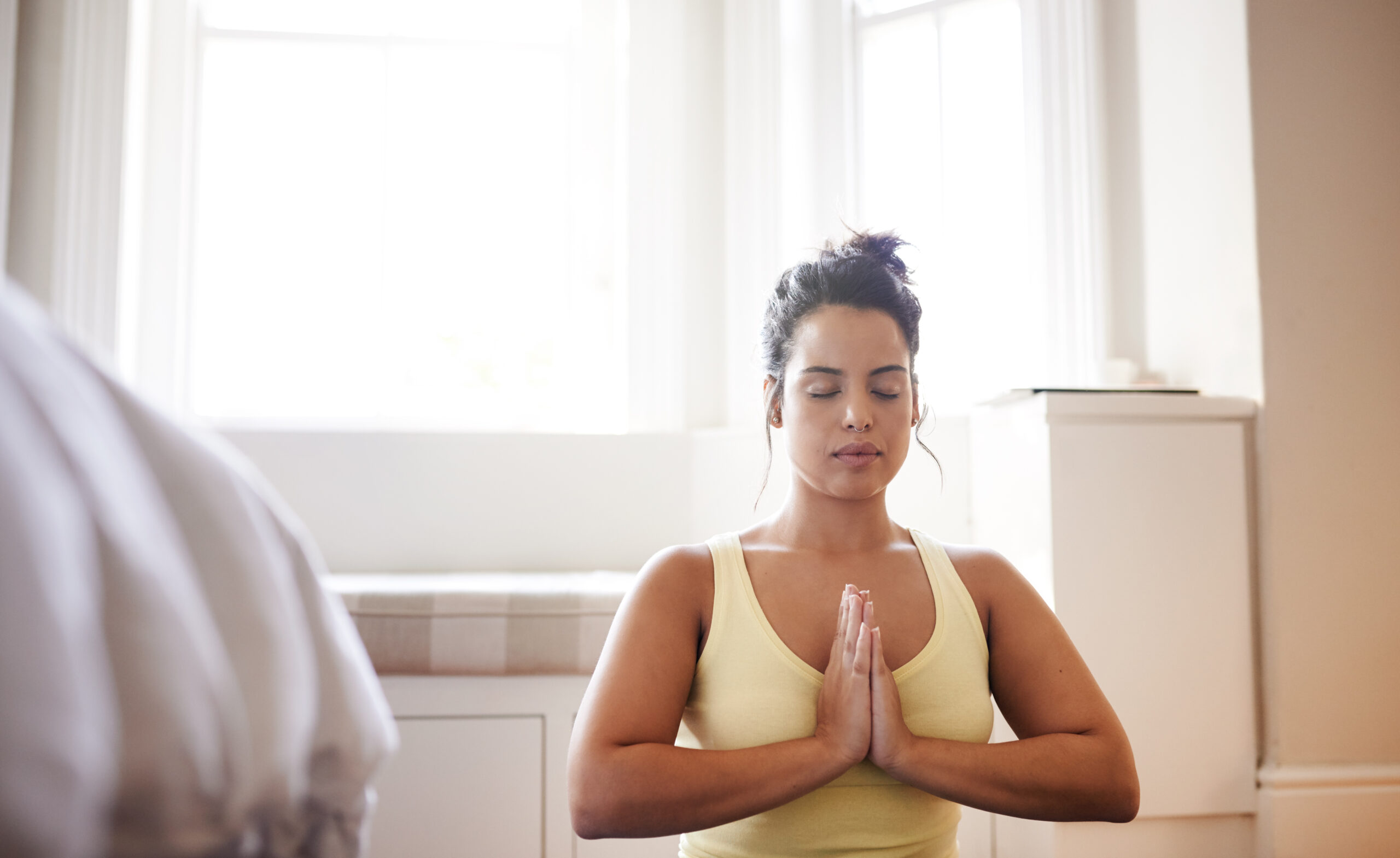 A woman meditating with her hands together over her chest.