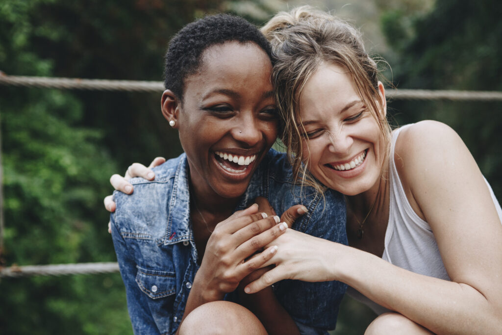 Two women laughing and giving a side hug.