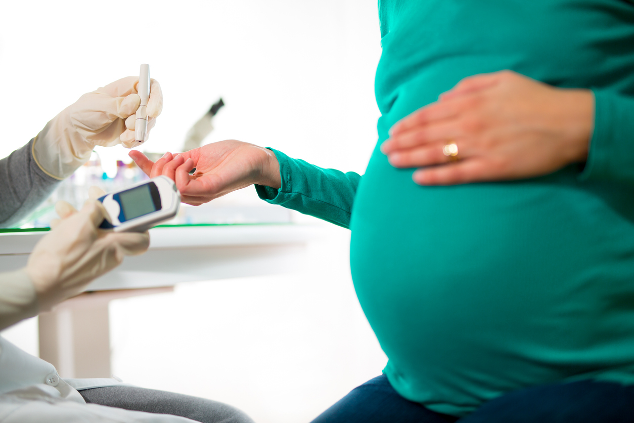 A pregnant woman has her blood sugar tested via a finger prick.
