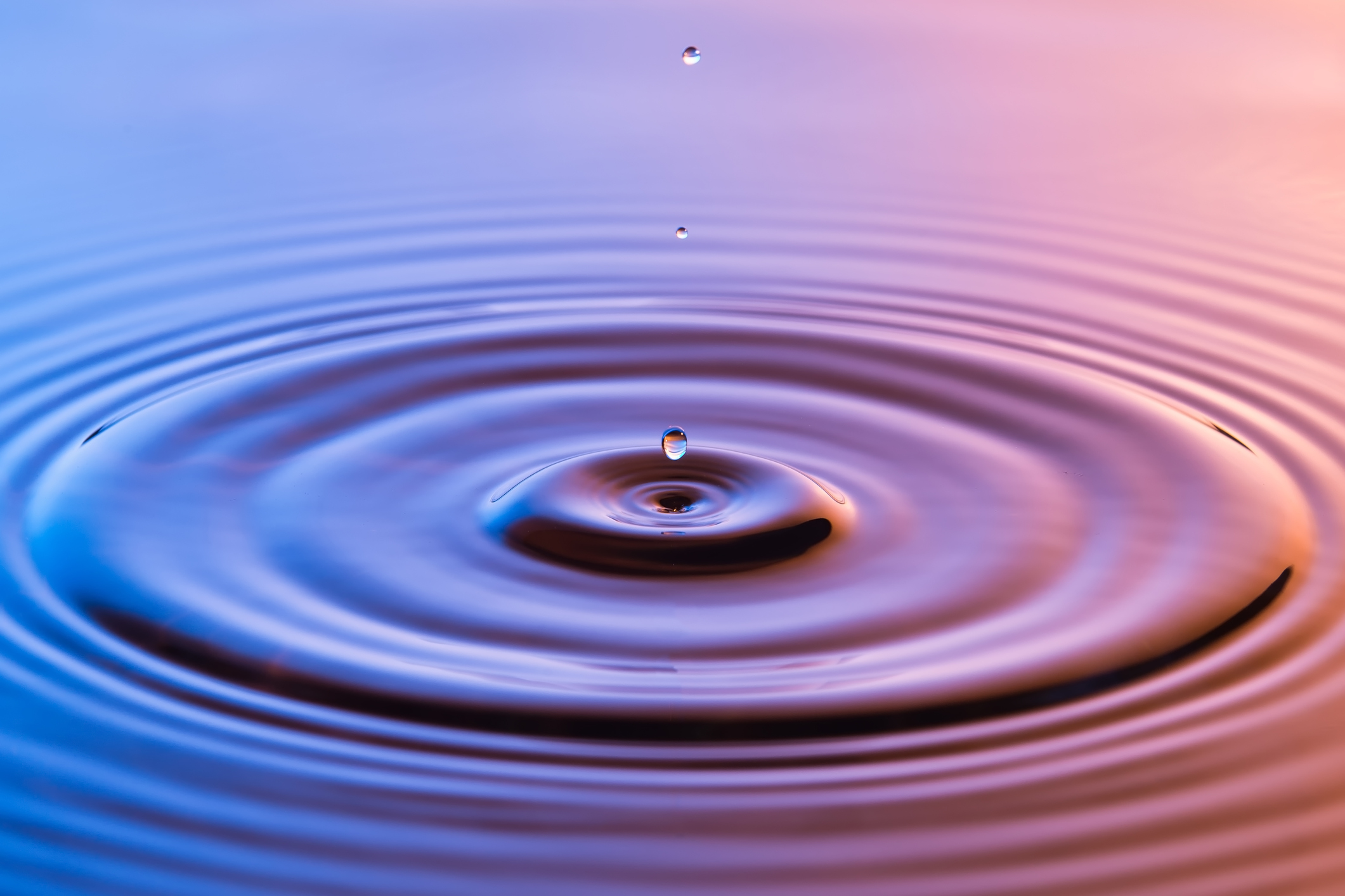 Water droplets falling into water making a rippling effect.