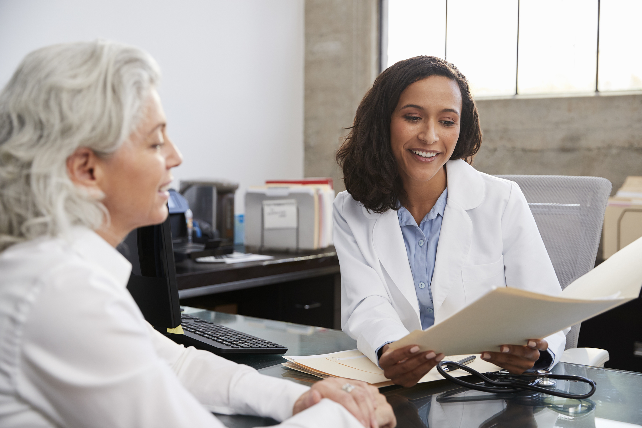 A doctor and a patient talking inside an office.