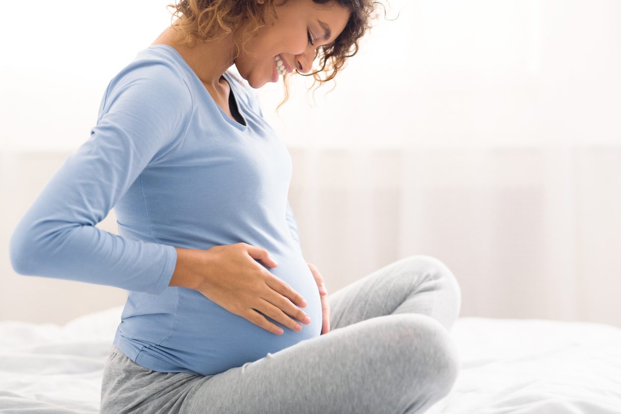 A pregnant woman with her hands on her belly.