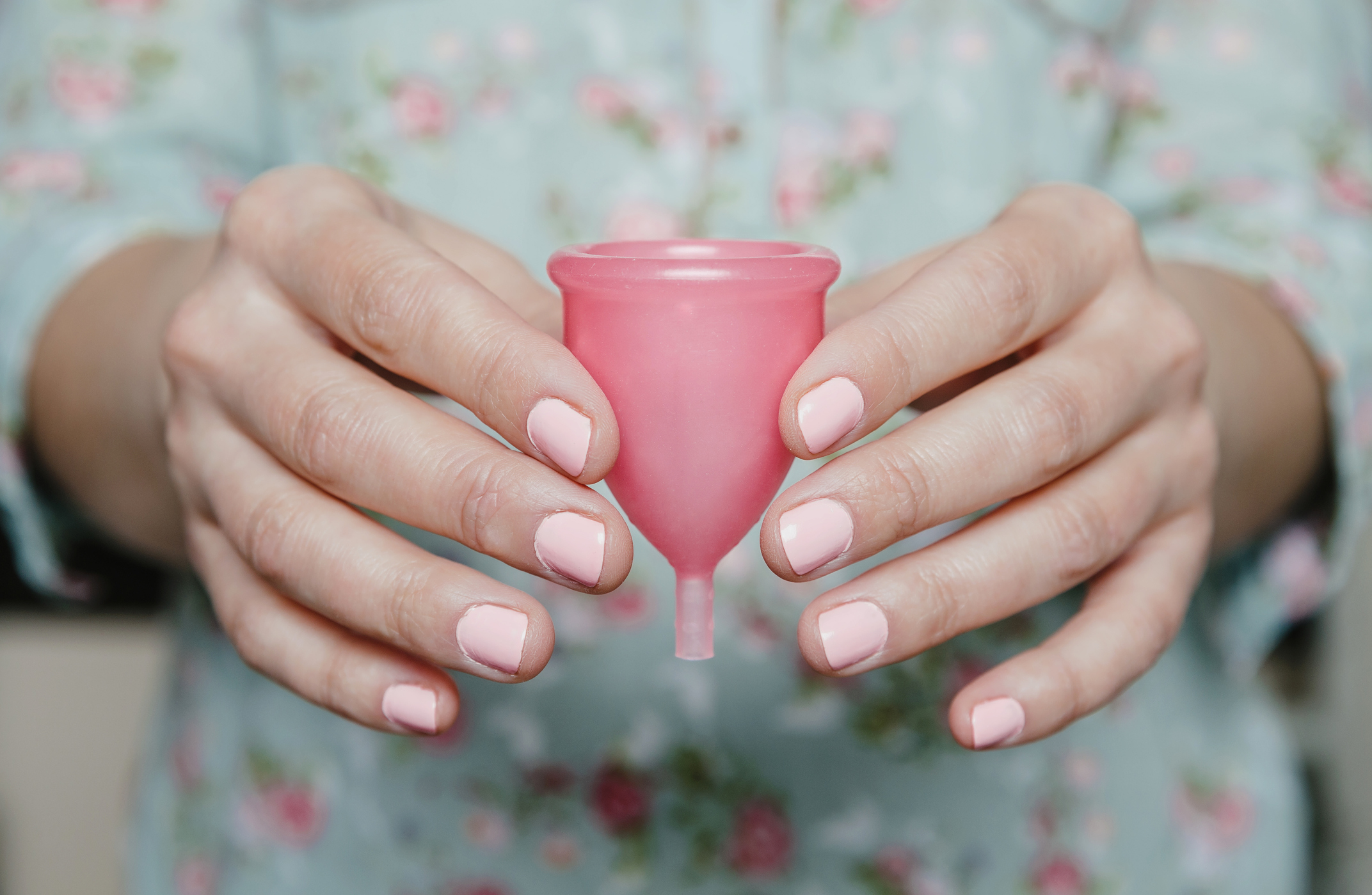 Two hands holding a period cup.