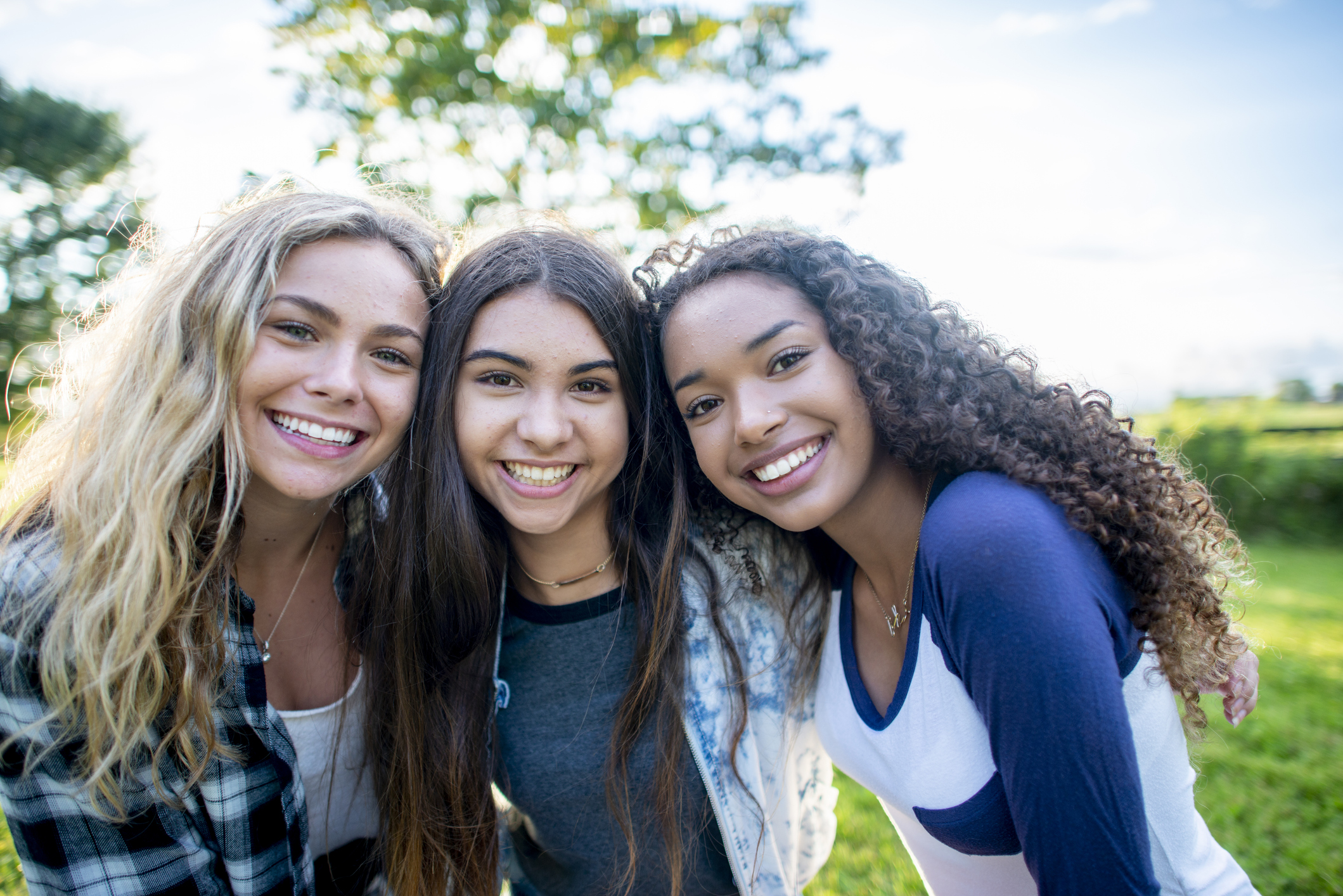 Three teenage girls smiling at the camera.