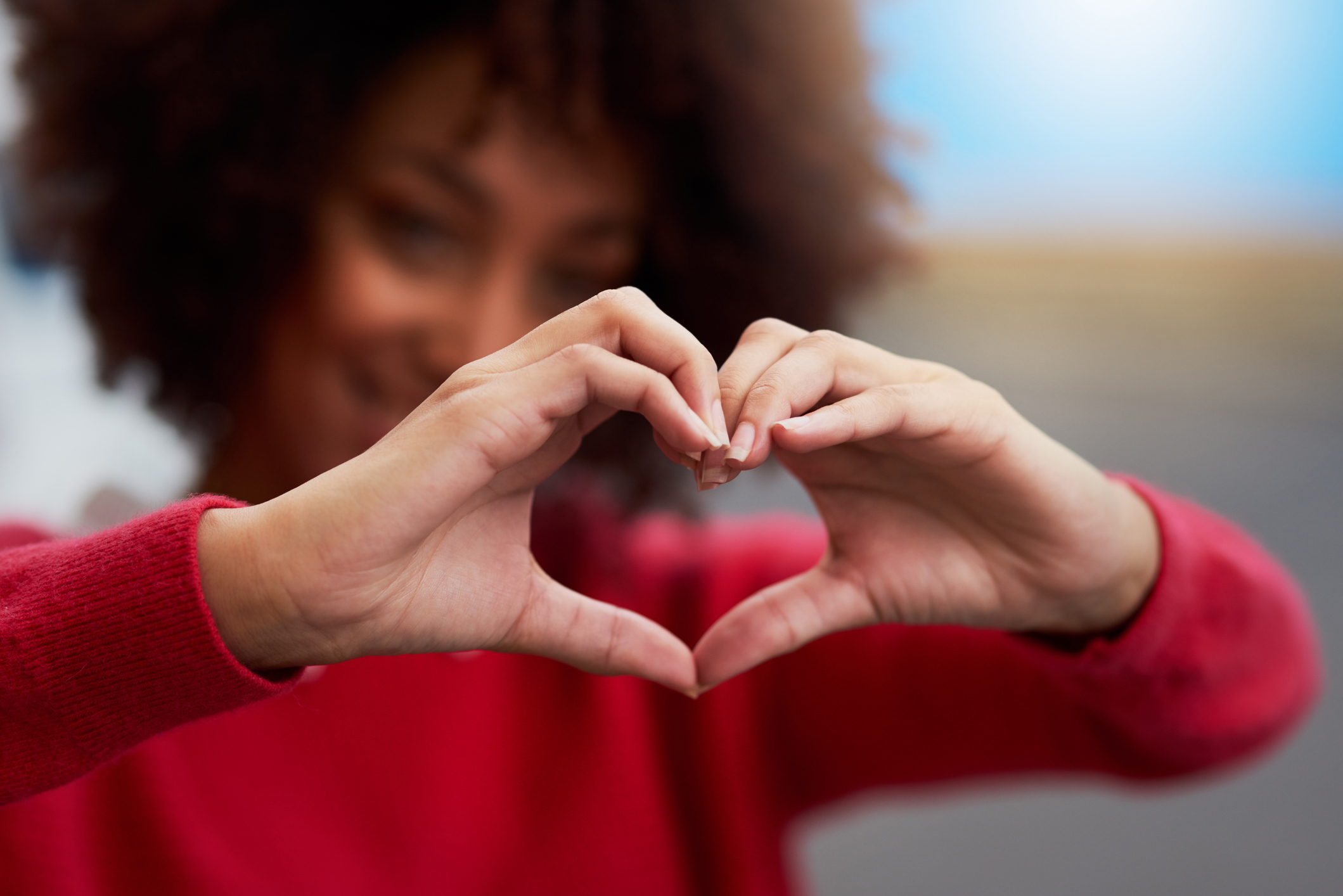 A woman making a heart shape with her hands.