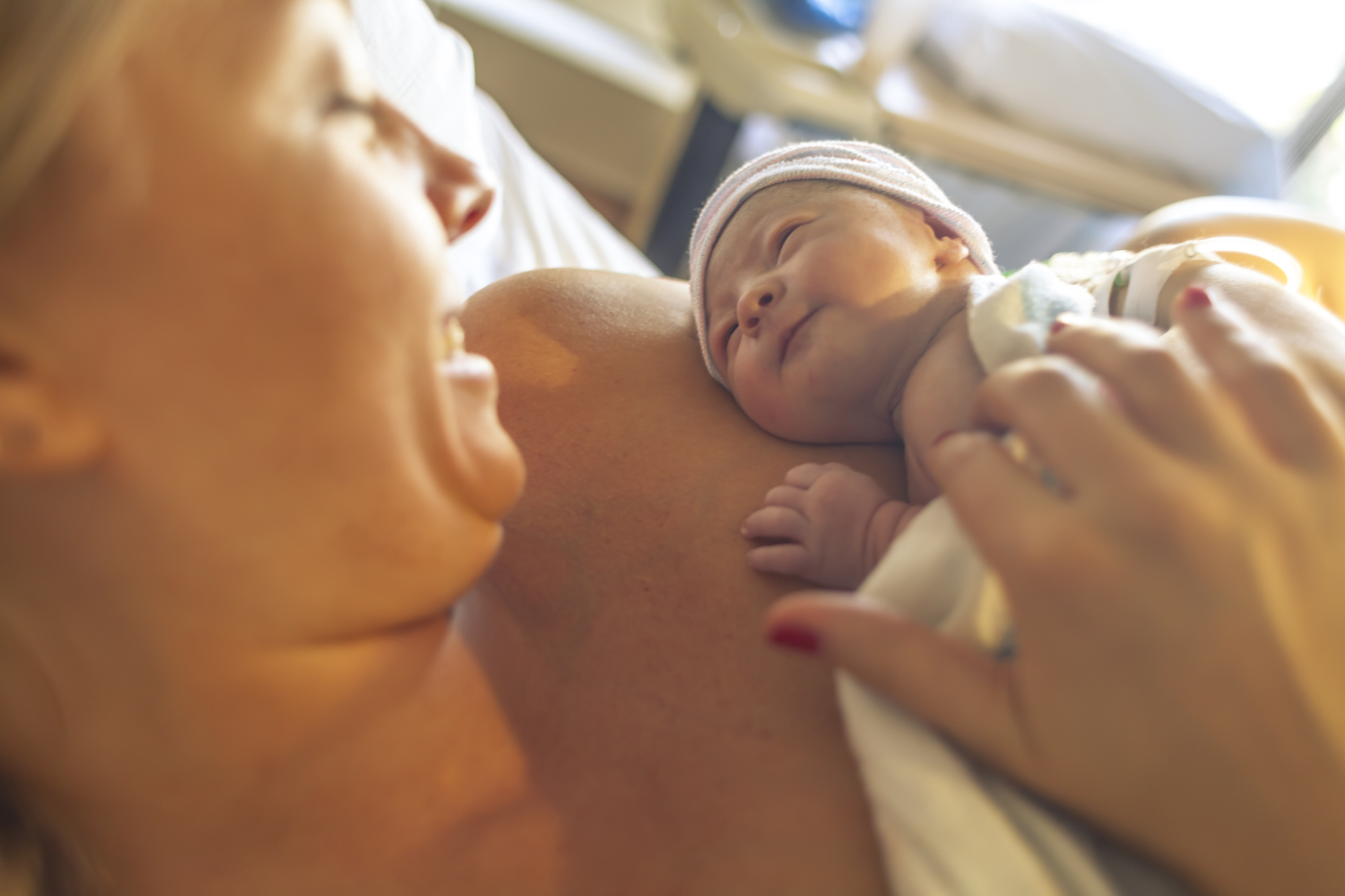 A woman with her newborn child resting on her arm.
