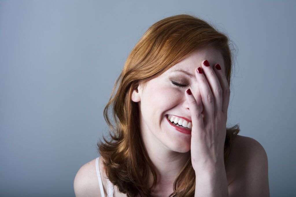 A woman laughing with her hand covering half of her face.