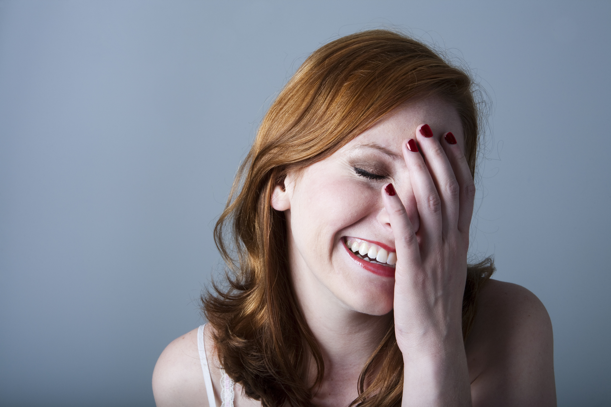 A woman laughing with her hand covering half of her face.