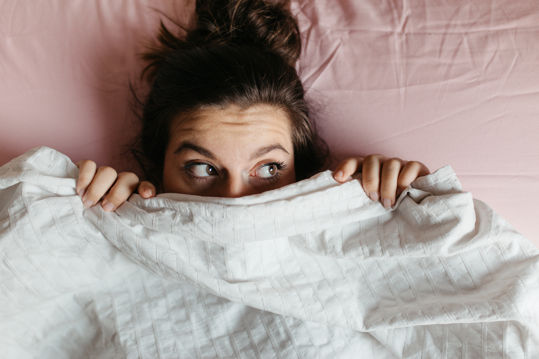 woman in bed with sheets covering part of her face